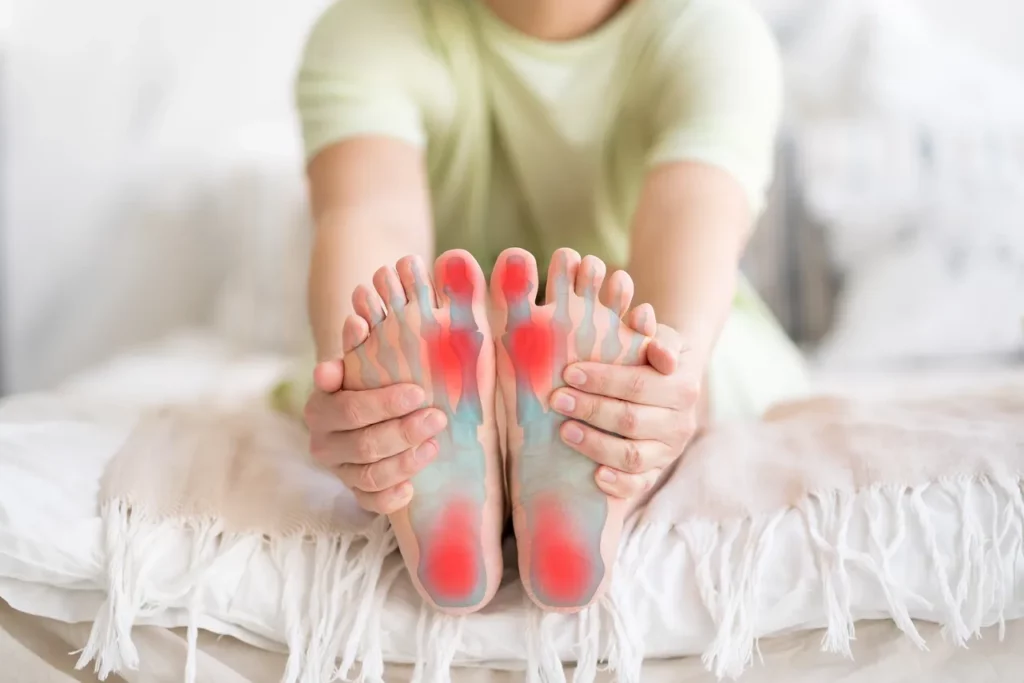 a woman is sitting on a bed with her feet in pain.