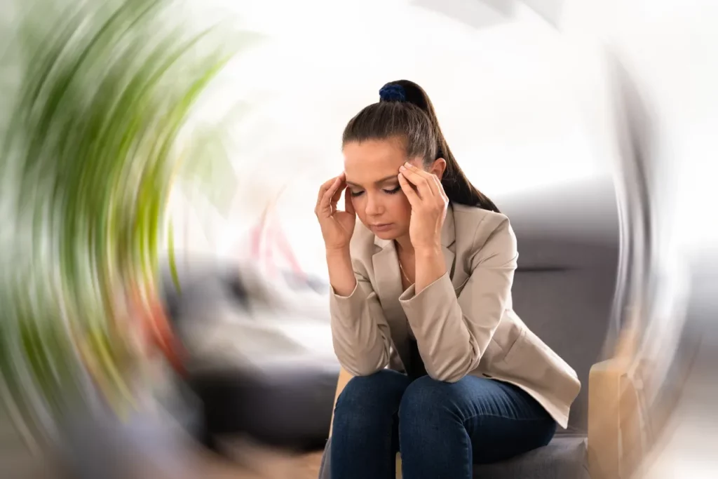 a woman sitting in a chair with her hands on her head.