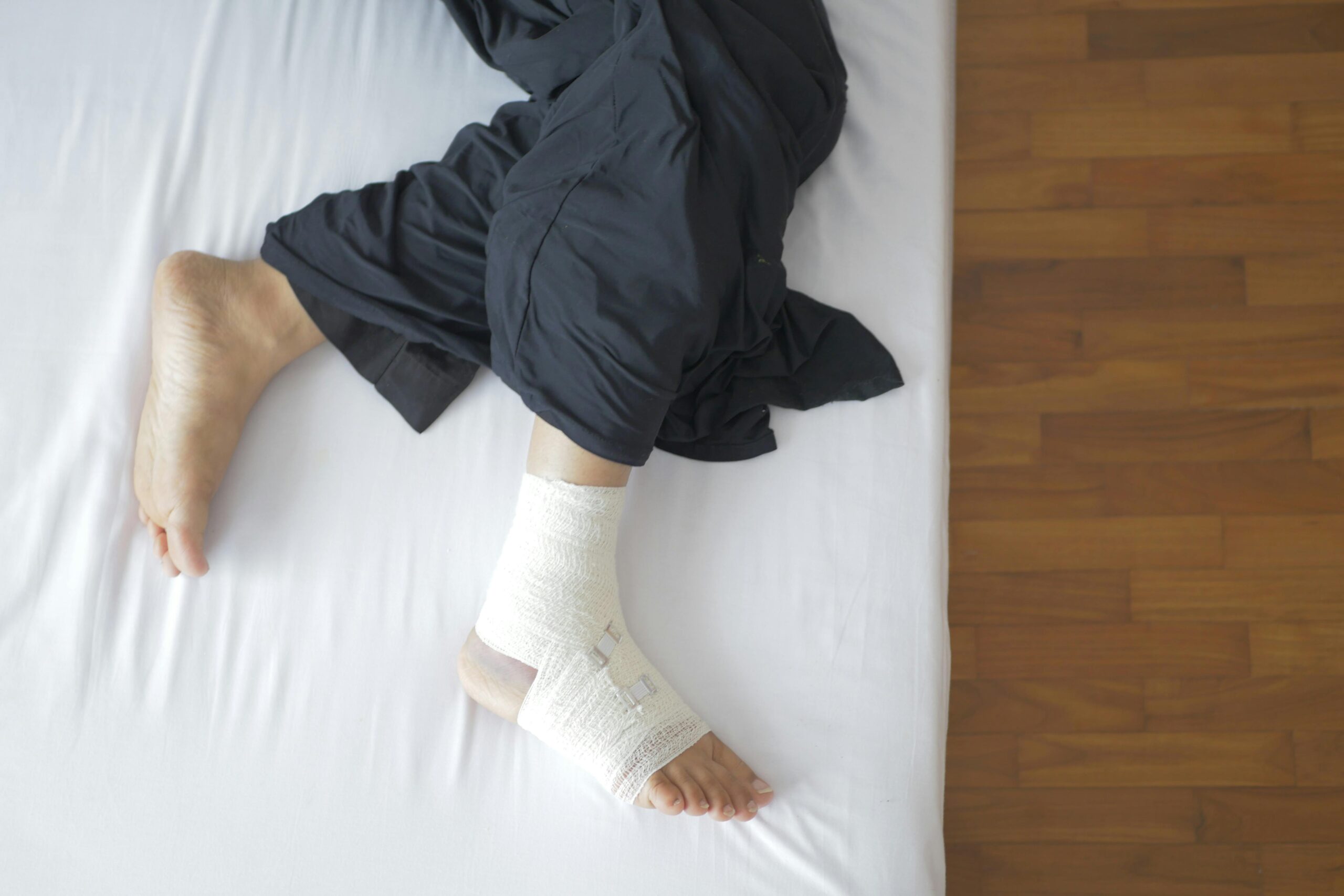 Close-up of a person lying on their side with one foot bandaged, illustrating a recovery moment related to physical therapy for Achilles tendonitis